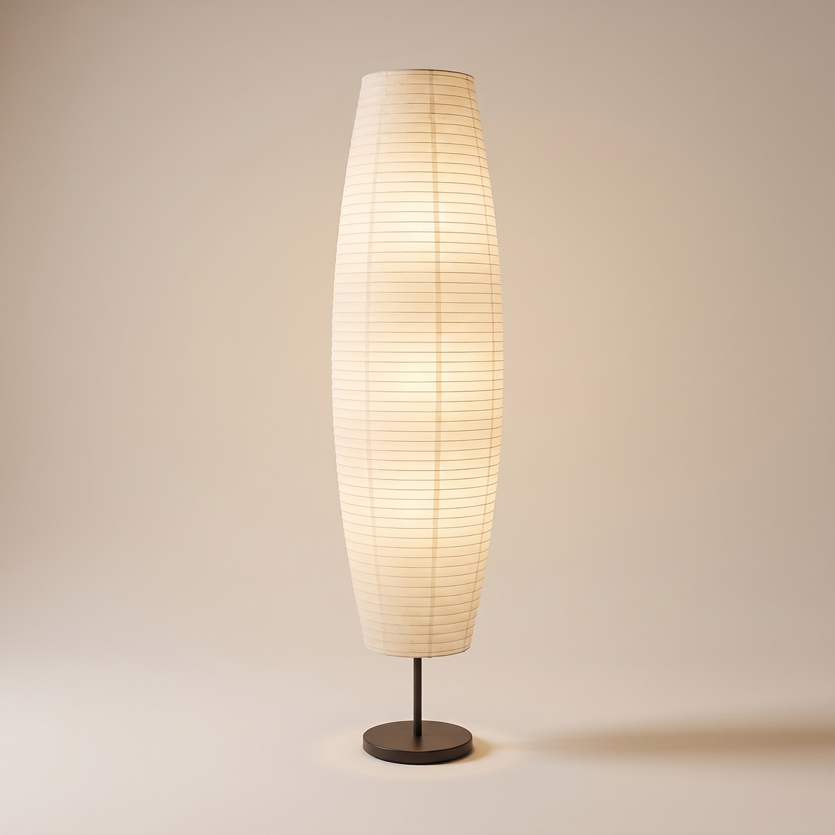 Rice paper column floor lamp, lit, on a warm neutral background