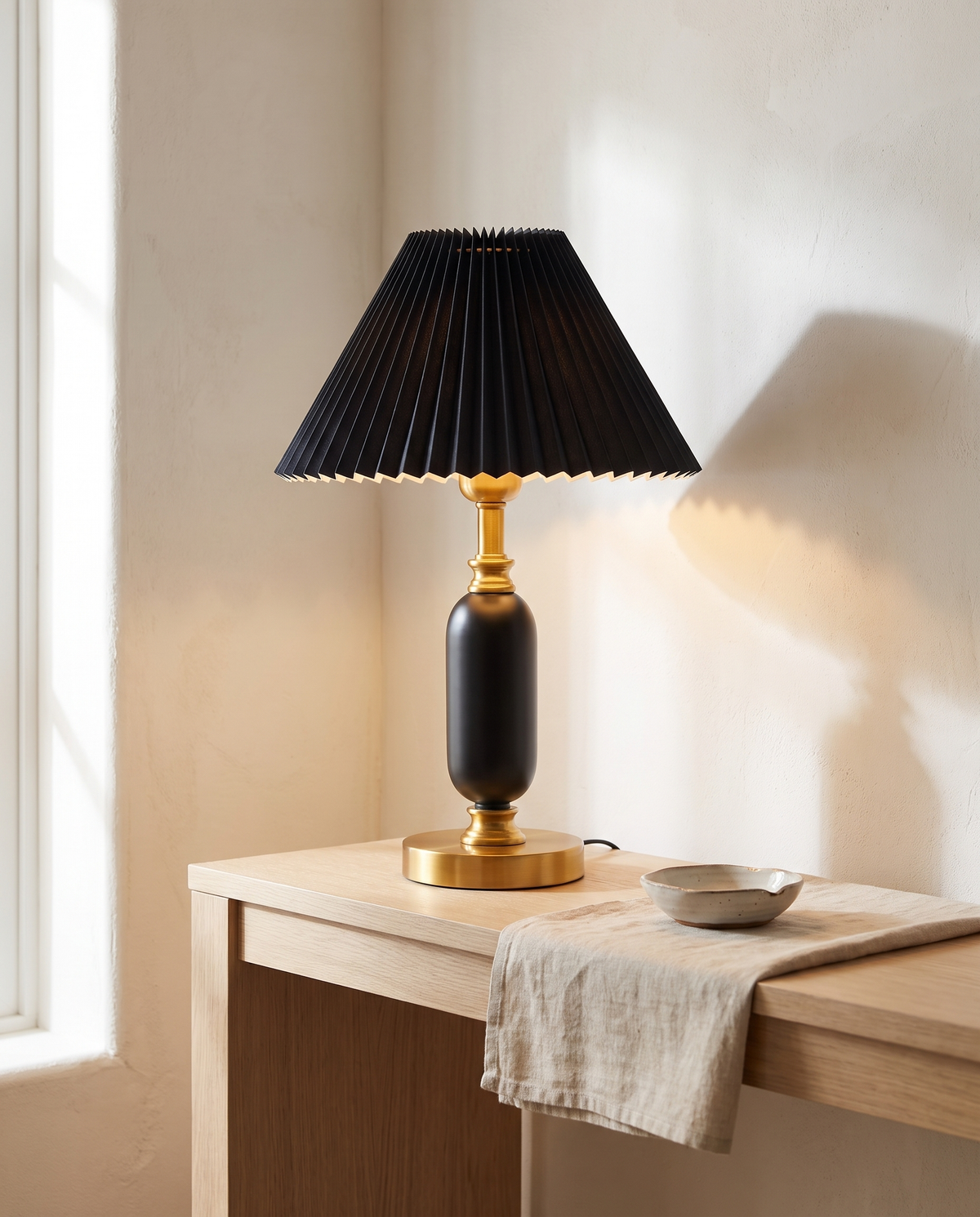 French pleated shade table lamp lit on a pale oak hallway console